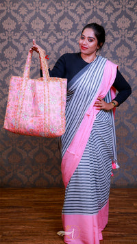 Woman holding a pink embroidered bag against a patterned wall.