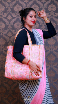 Woman holding a pink and white patterned bag against a decorative wall.