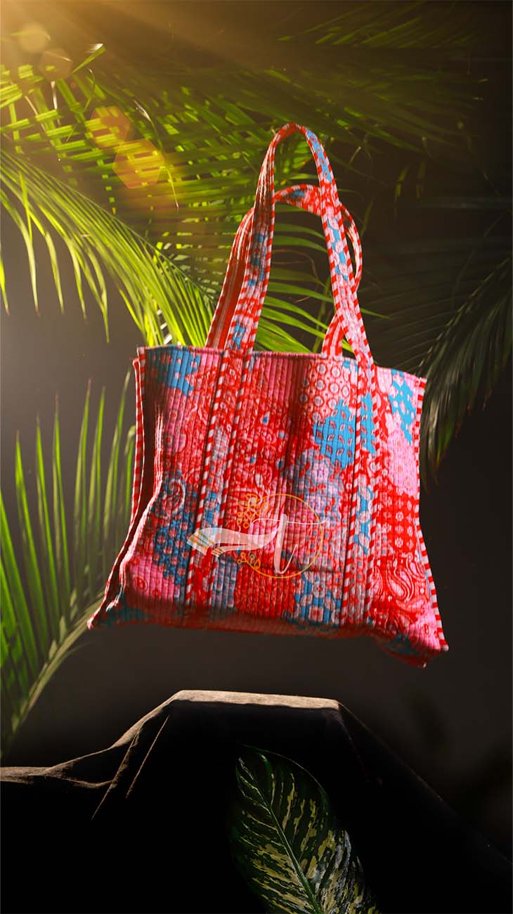 Floral patterned tote bag with a brand logo against a dark background with green foliage.