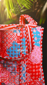 Red patterned bag with floral designs against a blurred green background