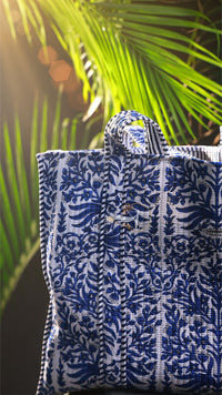 Blue and white patterned bag against a tropical background with palm leaves.