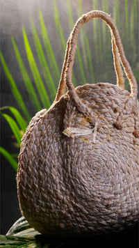 Woven basket with a handle on a leafy background