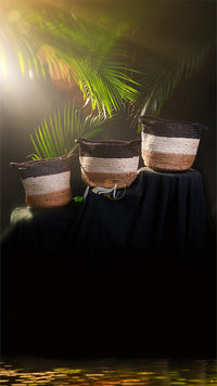 Three woven baskets on a dark surface with a blurred natural background