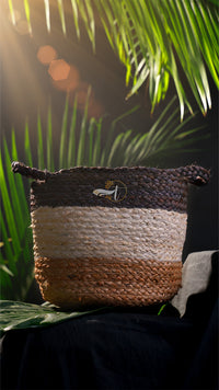 Woven basket with a logo on a dark background with green leaves
