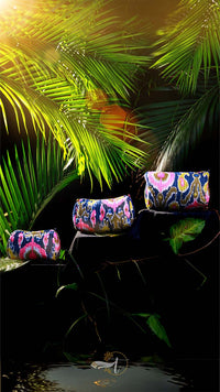 Colorful handbags on a reflective surface with green leaves in the background