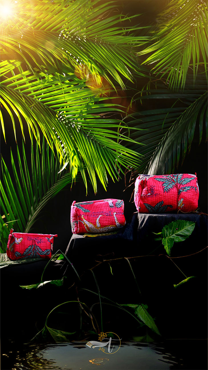 Red bags with floral patterns on a dark surface surrounded by green leaves