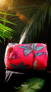 Pink quilt with tropical leaf pattern on a dark background