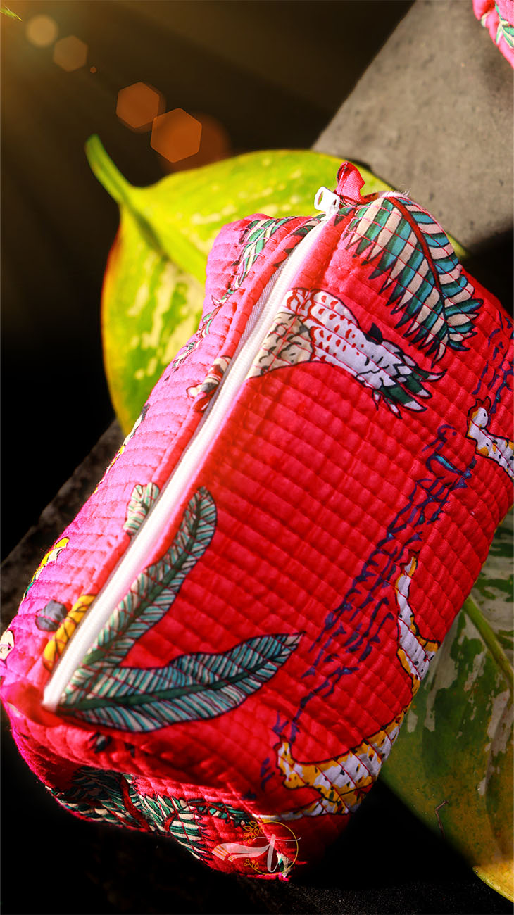 Red quilted pouch with floral patterns on a dark background