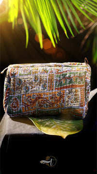 Decorative clutch bag with intricate patterns on a dark background with green leaves.