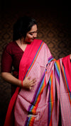 Woman wearing a pink saree with a colorful border against a dark background