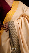 Close-up of a person wearing a beige saree with a yellow border.
