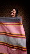 Woman holding a large fabric with colorful stripes against a dark background