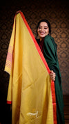 Woman holding a yellow and red patterned fabric against a dark background