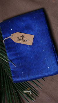 Blue fabric with a 'THANVI' tag on a brown surface