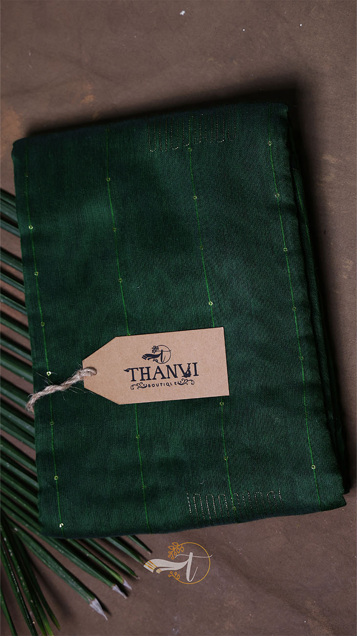 Green fabric with a Thanvi tag on a dark background