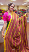 Woman holding a maroon saree with yellow stripes in a store setting