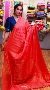 Woman wearing a red saree with a blue blouse in a store setting.