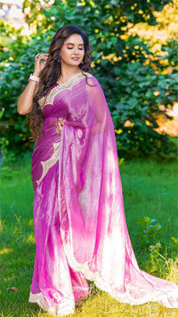 Woman wearing a pink and purple saree with a blurred green background