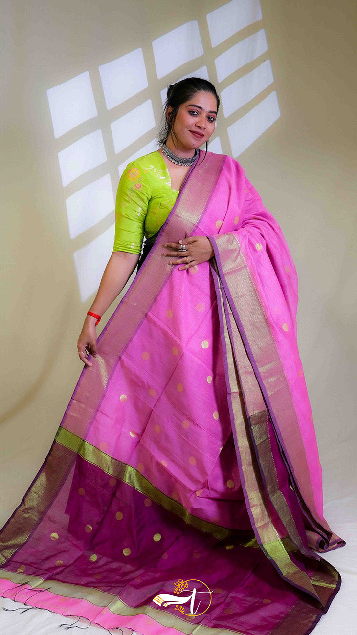 Woman wearing a pink saree with a green blouse against a neutral background