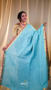 Woman holding a light blue saree with a plain background