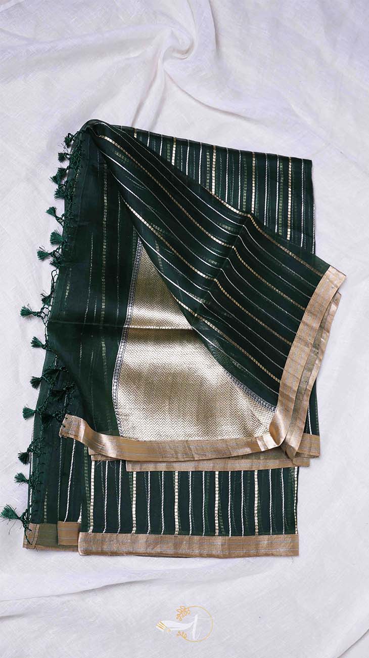 Green and gold saree with tassels on a white background