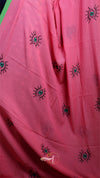 Pink fabric with black embroidered designs on a pink background