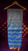 Blue and white patterned fabric on a hanger against a dark background with orange circular lights.