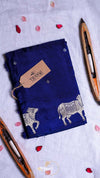 Blue fabric with cow designs and a tag on a light gray background
