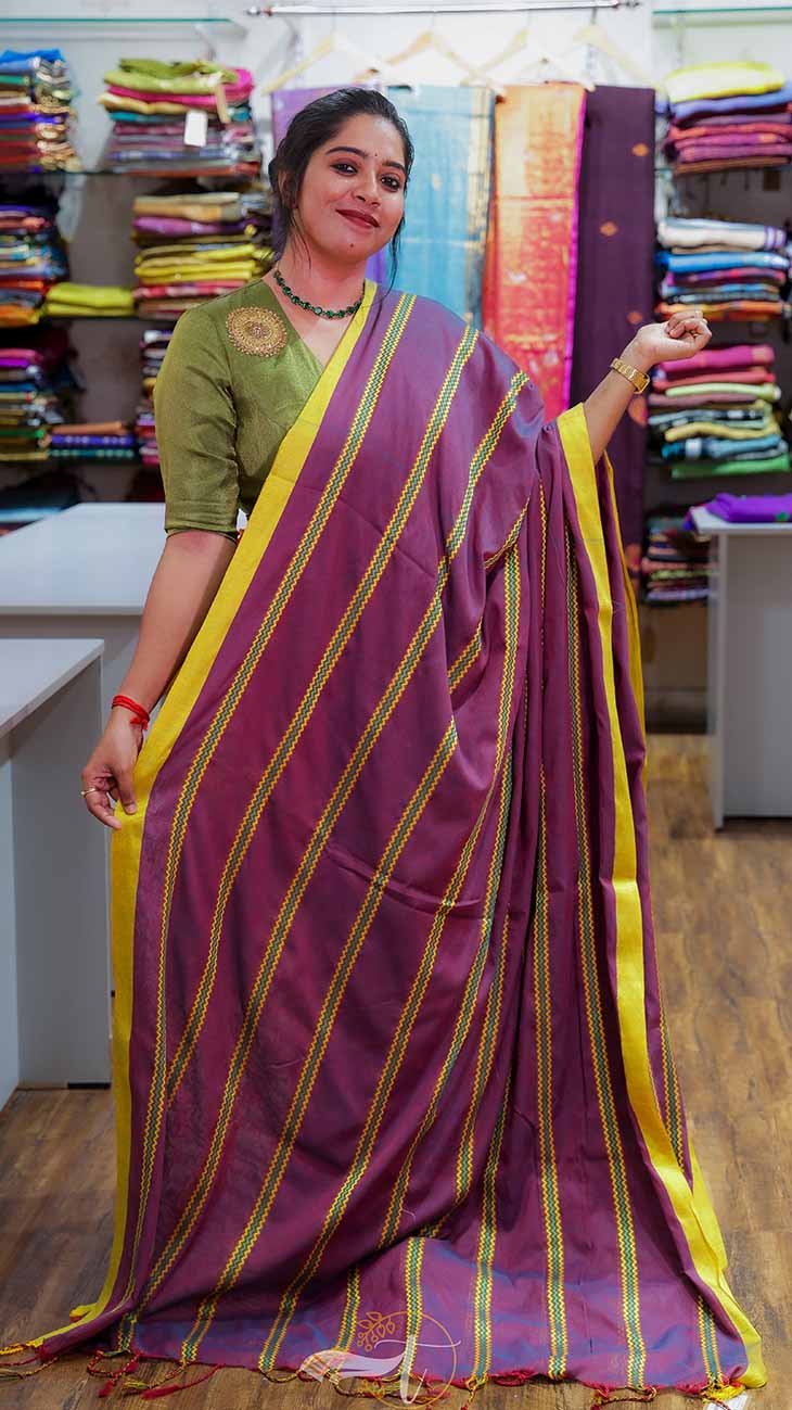 Woman wearing a purple saree with yellow stripes in a fabric store.