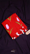 Red floral scarf with white tassels on a dark fabric background