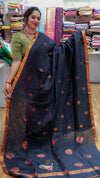 Woman holding a navy blue saree with gold patterns in a fabric store.