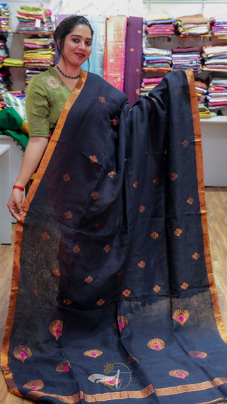 Woman holding a navy blue saree with gold patterns in a fabric store.