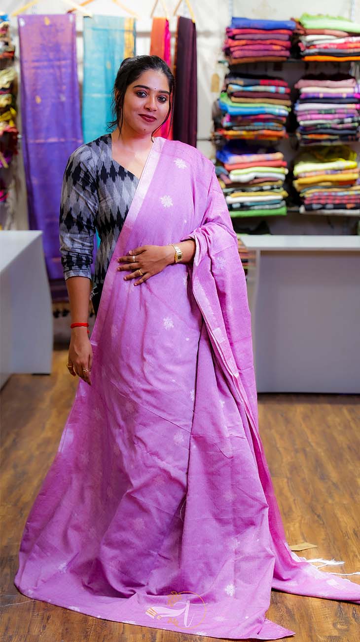Woman wearing a purple saree with a colorful fabric background