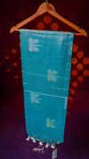 Turquoise scarf with white floral patterns on a wooden hanger against a dark background