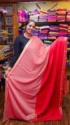 Woman holding a pink saree in a fabric store with colorful fabrics in the background.