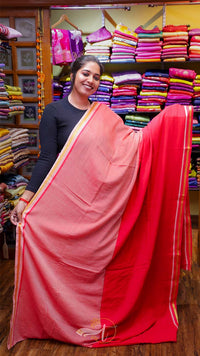 Woman holding a pink saree in a fabric store with colorful fabrics in the background.