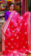 Woman holding a red saree with white patterns in a store setting