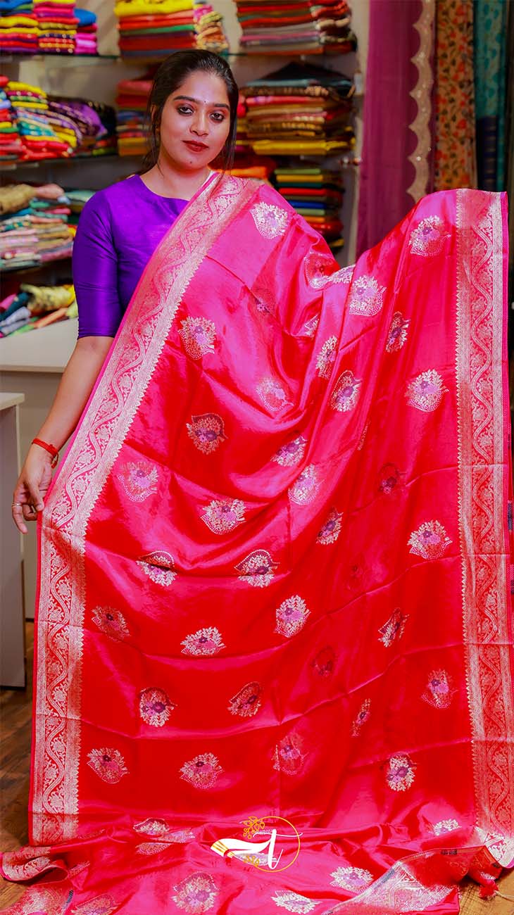 Woman holding a red saree with white patterns in a store setting