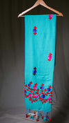 Turquoise scarf with floral embroidery on a hanger against a dark background