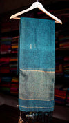 Blue fabric on a hanger with a blurred background of shelves.