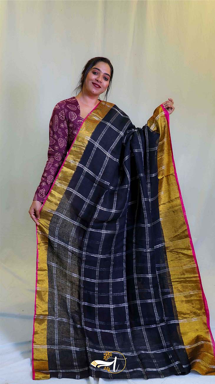 Woman holding a black checkered saree with gold border against a white background