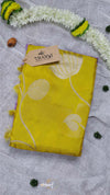 Yellow fabric with floral patterns on a gray surface with decorative elements.