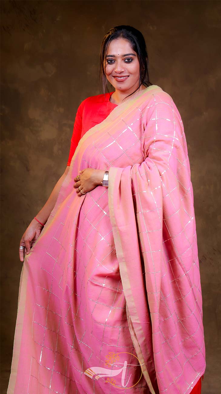 Woman wearing a pink saree with a brown background