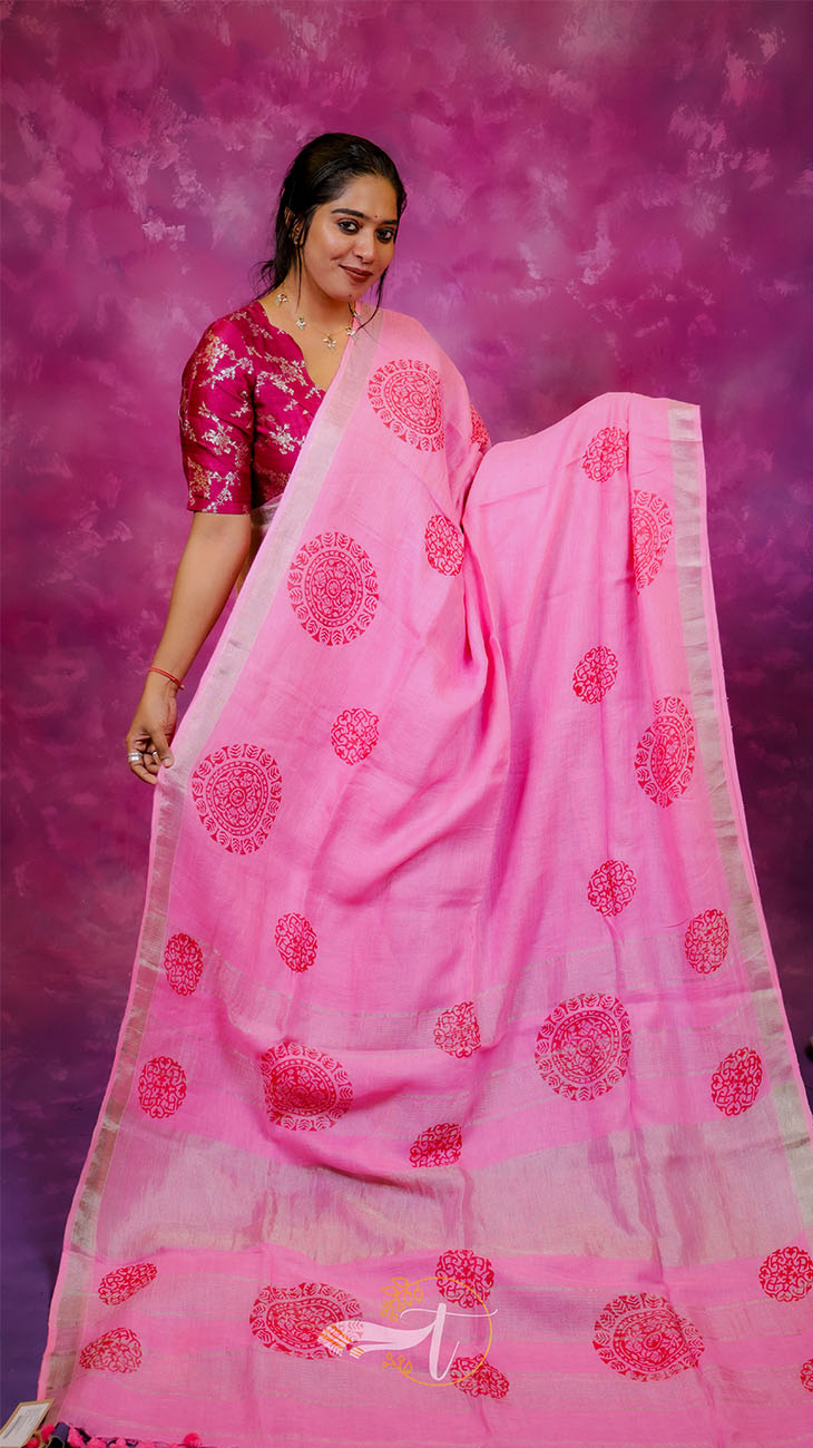 Woman wearing a pink saree with red patterns against a purple background