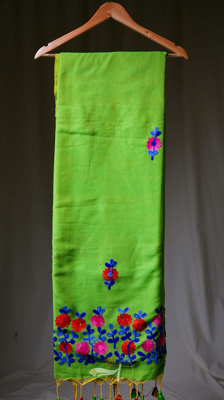 Green scarf with floral embroidery on a hanger against a gray background