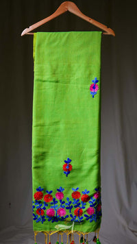Green scarf with floral embroidery on a hanger against a gray background