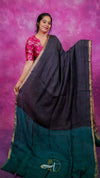Woman wearing a black and green saree with a pink background