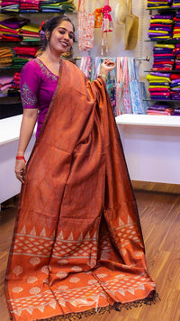 Woman wearing an orange saree with a purple blouse in a store setting.