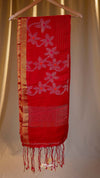 Red scarf with white floral patterns hanging on a wooden hanger against a beige background