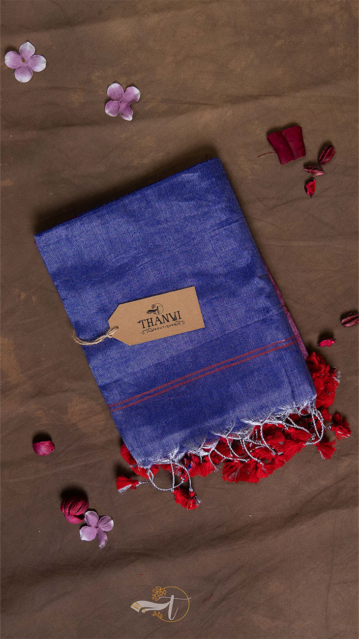 Blue towel with red tassels on a brown surface with flowers